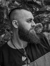 Viking warrior portrait with thick beard in front of a stone wall