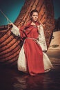 Viking woman in traditional clothes near drakkar