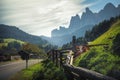 Village across a road with a caw sitting on the field and mountains in the background Royalty Free Stock Photo