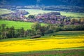 Village and agricultural landscape in spring may time. Sunny landscape, church, trees, and green and yellow fields