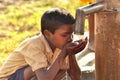 A village boy drinking tap water.