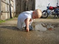 Village boy playing in a dirty puddle next to a barn in a grandmothers yard Royalty Free Stock Photo