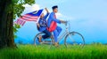 Village boy riding old bicycle at paddy field holding a Malaysian flag celebrating Independence Day Royalty Free Stock Photo