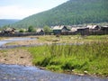 Siberian village dilapidated houses and fences, river channel and green hills