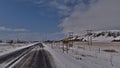 Village entrance of town Kirkjubaejarklaustur in southern Iceland on sunny winter day with ice-covered road and place-name sign.