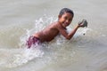 A village girl kid jumping on the river water with a handful of wet soil or mud at Majherchar,