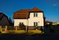 Village house with white facade and red rood seen from the street against deep blue sky in the background