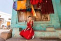 Village house and young woman sitting at front of colorful building in small indian town.