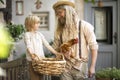 Village life. Country boy with Daddy brown chicken and a big basket in the yard near the front door.Summer day