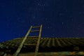 Village. Old wooden ladder leaning against the barn with a slate roof in the night star sky. The staircase leads to the Royalty Free Stock Photo