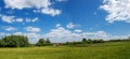Village panorama spring - spacious green meadow, blue sky with c Royalty Free Stock Photo