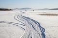 Trace from cars on a snowy lake with fishermen in the background Royalty Free Stock Photo