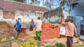 Group of men working together to lay red bricks on the wall of an old building Royalty Free Stock Photo