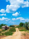 village road along the seashore, thatched huts, blue sky with cumulus white clouds
