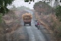 Village road in rural area with tractor carrying hay or dried grass