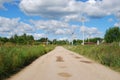 Village road to the village. White clouds in the sky. Power lines. Rural landscape. Russia. Royalty Free Stock Photo