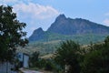 Village road with white house; country cottage against the backdrop of tall beautiful sharp blue mountains with peaks. Summer