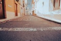 Village street in old Spanish town with grungy building exteriors lining the road and stop sign painted at end Royalty Free Stock Photo