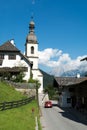 Village street with red car and bellfry in Alps