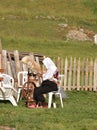 Village woman sitting outdoors weawing wool on vintage spindle stool