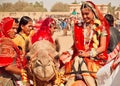 Village women in red sari riding the camels