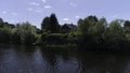 Village with wooden house built on the shore of a pond. Shot. Ecological place for living, small house, green trees and Royalty Free Stock Photo