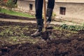 Villager with old clothes uses a spade to turn the clay and try to oxidize it. Autumn landscaping. Village boy jumps on a spade