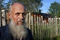 Villager stands behind picket fence on which dried empty tins