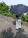 a villager with umbrella wathing his farm in the sun