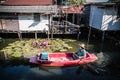 Villagers row a boat in a canal to enter the Hua Takhe Market Community House, Thailand.