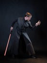 A villain with a red lightsaber, a young man in a long robe does fighting poses,