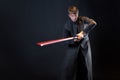 A villain with a red lightsaber, a young man in a long robe does fighting poses,