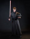 A villain with a red lightsaber, a young man in a long robe does fighting poses,