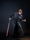 A villain with a red lightsaber, a young man in a long robe does fighting poses,