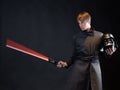 A villain with a red lightsaber, a young man in a long robe does fighting poses,