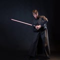 A villain with a red lightsaber, a young man in a long robe does fighting poses, Royalty Free Stock Photo