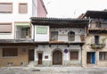 An old and traditional house with a stone archway at the front door and a wooden beamed balcony decorated with old blue ceramic