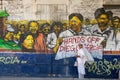 Woman stands at the street with political poster `Hands off Diego Garcia` painted at the wall in Ville Noire, Mauritius island. Royalty Free Stock Photo