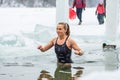 Beautiful blonde hair girl or woman ice bathing in the freezing cold water of a frozen lake