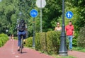 Girl with helmet cycling on the bike road and couple of pedestrians walking on the walkway