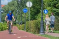 Man with helmet cycling on the bike road and young couple of pedestrians walking on the walkway