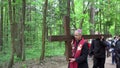 Priest in soutane and old grey head man carry cross like Jesus Christ