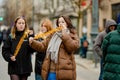 VILNIUS, LITHUANIA - MARCH 4, 2022: Cheerful young women eating fried potato on a stick on cold winter day outdoors