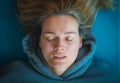 Portrait of a beautiful blond Caucasian girl with a blue sweatshirt lying on a mat, breathing and meditating