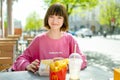 VILNIUS, LITHUANIA - MAY 2022: Smiling teenage girl sitting by outdoor table of McDonalds restaurant Royalty Free Stock Photo