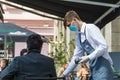 Waiter with a mask serving client at the table