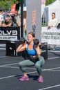 Beautiful athletic muscular Caucasian girl in green leggings and blue top weigh lifting or weightlifting