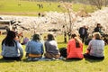 Vilnius, Lithuania - 04 22 2019: Young women sitting on green lawn enjoying blooming sakura trees at Sugihara park