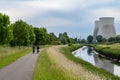 Vilvoorde, Flemish Brabant, Belgium - Cyclist on a bicycle trail at the banks of the river Senne with two powerplant chimneys in