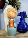 Vimtage Wooden Figurine of a Boy in a Blue Suite and Orange Vest, Holding a Flower, and a Blue Glass Perfume Bottle Royalty Free Stock Photo